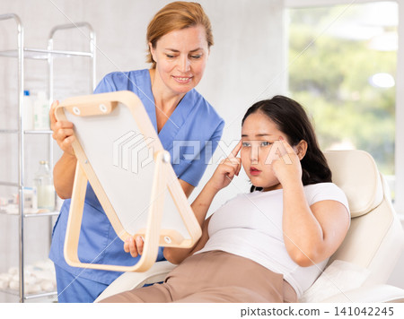 Female doctor giving consultation about injection for lips to female patient in aesthetic clinic Female doctor giving consultation about injection for lips to female patient in aesthetic clinic 141042245