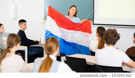 Geography lesson in school class - teacher talks about Netherlands, holding flag in his hands Geography lesson in school class - teacher talks about Netherlands, holding flag in his hands 141042302