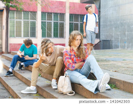 Couple of teenagers quarreling while sitting on stairs 141042303