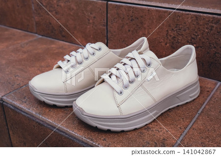 Fresh beige leather sneakers without brand marks displayed. For design templates online shops and sustainability-themed marketing. Clean blank sneakers Fresh beige leather sneakers without brand marks displayed. For design templates online shops and sustainability-themed marketing. Clean blank sneakers 141042867