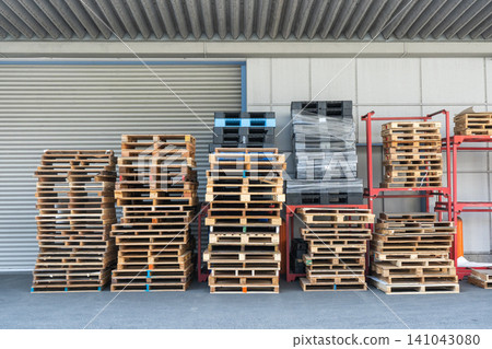 Wooden and plastic pallets piled up at the warehouse entrance. Wooden and plastic pallets piled up at the warehouse entrance. 141043080