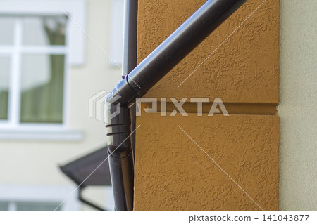 Roofing steel gutter rain system on building corner on light copy space background. Roofing, construction, drainage pipes installation concept. Roofing steel gutter rain system on building corner on light copy space background. Roofing, construction, drainage pipes installation concept. 141043877