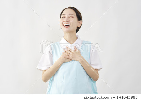 A female caregiver looks relieved against a white background. A female caregiver looks relieved against a white background. 141043985