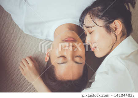 A couple's sleep image, a bird's-eye view portrait of two people sleeping on a rug, eyes closed and snuggled together. A couple's sleep image, a bird's-eye view portrait of two people sleeping on a rug, eyes closed and snuggled together. 141044022