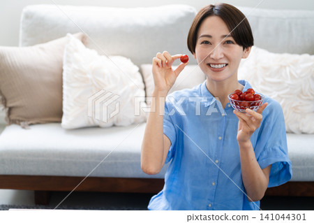 Young woman eating cherry tomatoes lifestyle image Young woman eating cherry tomatoes lifestyle image 141044301