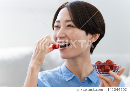 年輕女子吃櫻桃番茄 — 生活方式形象 年輕女子吃櫻桃番茄 — 生活方式形象 141044302