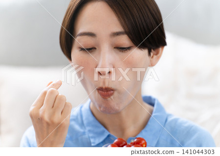 年輕女子吃櫻桃番茄 — 生活方式形象 年輕女子吃櫻桃番茄 — 生活方式形象 141044303