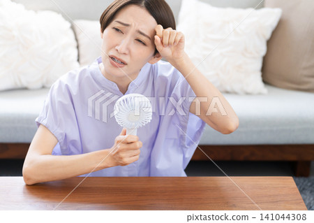 Young woman using a hand fan Lifestyle image Young woman using a hand fan Lifestyle image 141044308