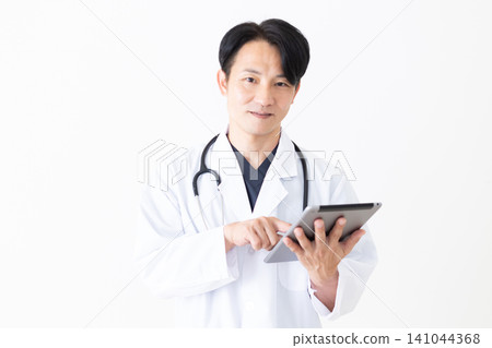 A middle-aged male doctor in a white coat holding a tablet. A middle-aged male doctor in a white coat holding a tablet. 141044368