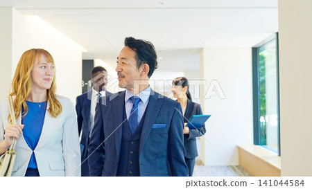 Group of multinational business people walking through a building and talking Group of multinational business people walking through a building and talking 141044584