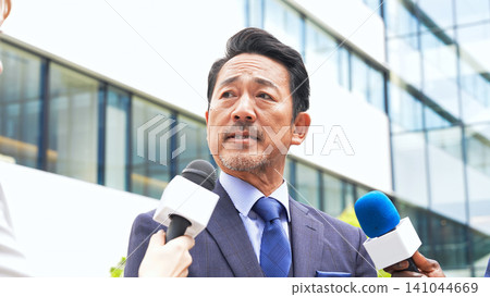 中年男子在大樓前接受採訪 中年男子在大樓前接受採訪 141044669