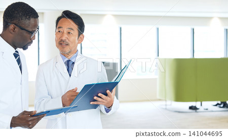 身穿白大褂的多國工程師在大廳交談 身穿白大褂的多國工程師在大廳交談 141044695