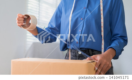 Online merchant applying packing tape to shipping box preparing ecommerce order for customer delivery Online merchant applying packing tape to shipping box preparing ecommerce order for customer delivery 141045171