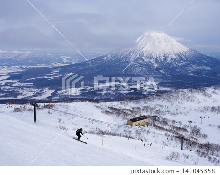 Skiers skiing down Wonderland at Niseko Village Ski Resort with Mount Yotei in the background. Skiers skiing down Wonderland at Niseko Village Ski Resort with Mount Yotei in the background. 141045358