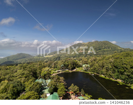 View of a large green area with a lake and mountains under the sky 141046236