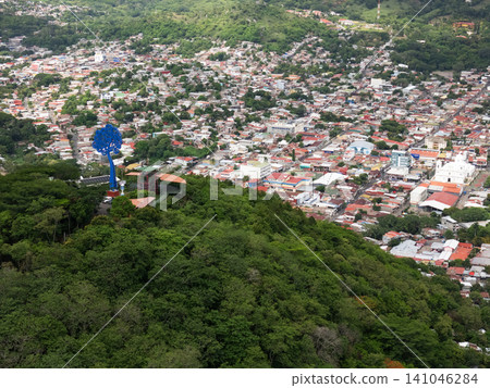 View from mountain showing city below and large statue in distance 141046284