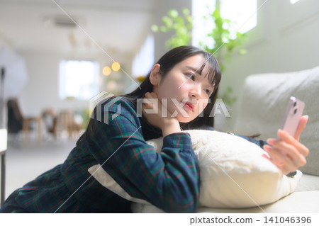 A woman watching a smartphone on a sofa 141046396