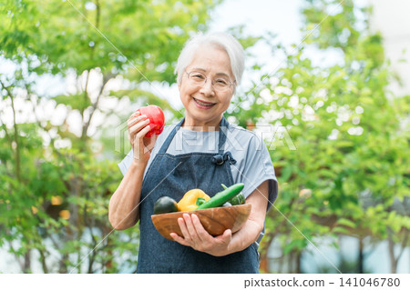 一位頭髮花白的老婦人喜歡在自家後院種花。 一位頭髮花白的老婦人喜歡在自家後院種花。 141046780