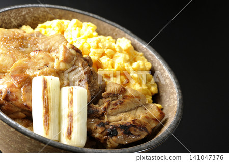 A bowl of scrambled eggs, grilled green onions, and charcoal-grilled chicken photographed against a black background. A bowl of scrambled eggs, grilled green onions, and charcoal-grilled chicken photographed against a black background. 141047376