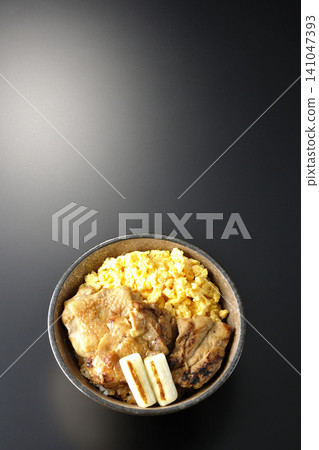 A bowl of scrambled eggs, grilled green onions, and charcoal-grilled chicken photographed against a black background. A bowl of scrambled eggs, grilled green onions, and charcoal-grilled chicken photographed against a black background. 141047393