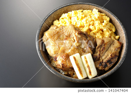 A bowl of scrambled eggs, grilled green onions, and charcoal-grilled chicken photographed against a black background. A bowl of scrambled eggs, grilled green onions, and charcoal-grilled chicken photographed against a black background. 141047404