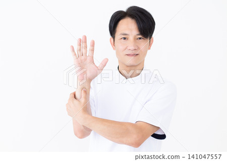 A middle-aged male acupuncturist/osteopath in a white coat pressing on pressure points on the arm. A middle-aged male acupuncturist/osteopath in a white coat pressing on pressure points on the arm. 141047557