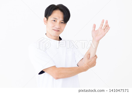 一位身穿白大褂的中年男性針灸師/整骨師正在按壓手臂上的穴位。 一位身穿白大褂的中年男性針灸師/整骨師正在按壓手臂上的穴位。 141047571