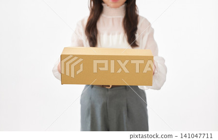 一位二十多歲的女子抱著一個紙箱。 一位二十多歲的女子抱著一個紙箱。 141047711