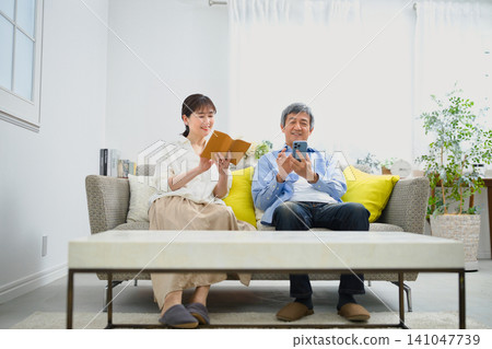 一對老年夫婦在沙發上放鬆休息。 一對老年夫婦在沙發上放鬆休息。 141047739