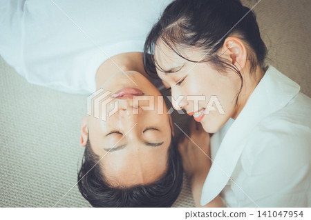 一張俯拍的情侶肖像,描繪了女友溫柔地凝視著睡在地毯上的男友的臉龐,一幅美麗的睡眠與美的畫面。 一張俯拍的情侶肖像,描繪了女友溫柔地凝視著睡在地毯上的男友的臉龐,一幅美麗的睡眠與美的畫面。 141047954