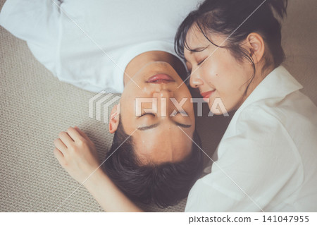 一張俯拍的情侶肖像照,展現了他們躺在地毯上閉目養神的優美身姿。 一張俯拍的情侶肖像照,展現了他們躺在地毯上閉目養神的優美身姿。 141047955