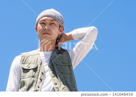 A male worker in work clothes stands against a blue sky. A male worker in work clothes stands against a blue sky. 141048459