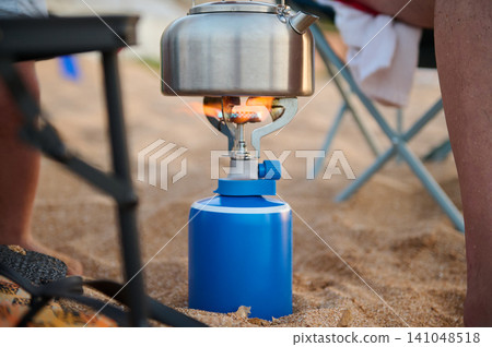 Portable camping stove boiling a kettle on the beach during an outdoor summer camping trip Portable camping stove boiling a kettle on the beach during an outdoor summer camping trip 141048518
