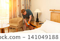 Blonde man in T-shirt and shorts cleaning his apartment on a weekend day off 141049188