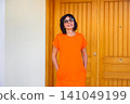Loving wife smiling warmly as she greets someone on the front porch of a cozy home 141049199