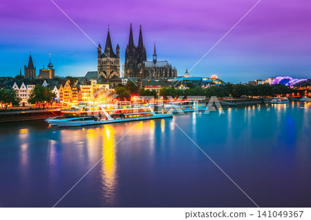 Cologne, Germany. Great St. Martin Church And Dom In Cologne At Evening With Reflection In River Rhine. Evening Blue Hour Cologne, Germany. Great St. Martin Church And Dom In Cologne At Evening With Reflection In River Rhine. Evening Blue Hour 141049367