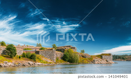 eautiful wide view from the water showing the historic stone walls and grassy fortifications of the Suomenlinna sea fortress under a sweeping blue sky eautiful wide view from the water showing the historic stone walls and grassy fortifications of the Suomenlinna sea fortress under a sweeping blue sky 141049401