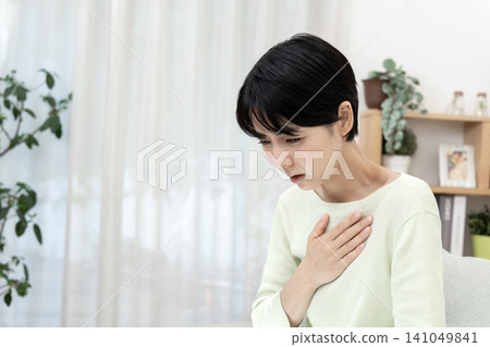 A young woman clutches her chest, suffering from heartburn and nausea due to reflux esophagitis. A young woman clutches her chest, suffering from heartburn and nausea due to reflux esophagitis. 141049841