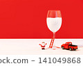 Miniature Santa figurine climbing a small ladder leaning against a snow-filled wine glass 141049868