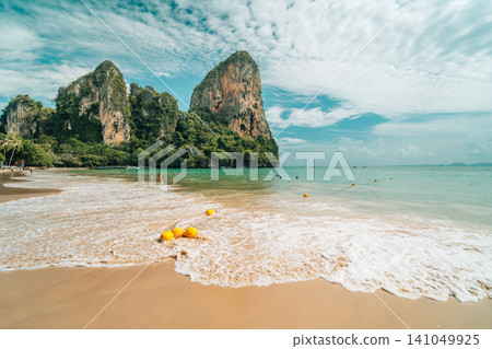 Scenic tropical beach with yellow buoys in the water and towering limestone cliffs in Scenic tropical beach with yellow buoys in the water and towering limestone cliffs in 141049925