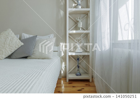 Bright Bedroom Corner with Wooden Shelving and White Curtains Bright Bedroom Corner with Wooden Shelving and White Curtains 141050251