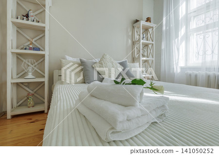 Cozy Bedroom Interior with Wooden Shelving and Towels on Bed 141050252