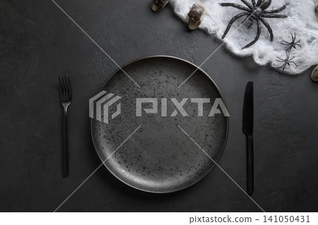 Halloween black table setting with spider, skull and web. View from above. Halloween black table setting with spider, skull and web. View from above. 141050431