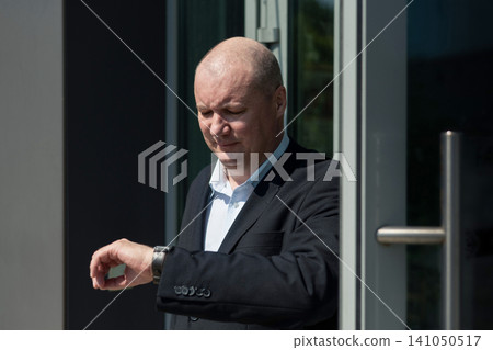 Businessman checking wristwatch before meeting Businessman checking wristwatch before meeting 141050517