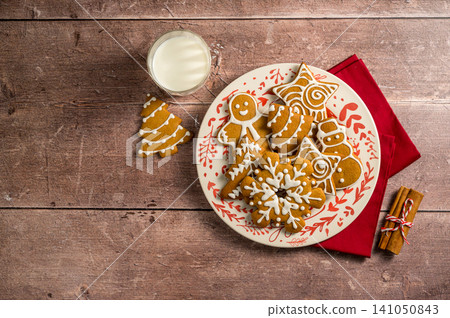 Holiday background. Christmas gingerbread cookies in a plate with glass of milk. Flat lay Holiday background. Christmas gingerbread cookies in a plate with glass of milk. Flat lay 141050843