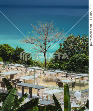 Elevated view of an empty seaside restaurant patio overlooking bright turquoise water. Elevated view of an empty seaside restaurant patio overlooking bright turquoise water. 141051362