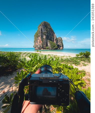 POV of a photographer holding a camera capturing a tropical beach and limestone rock. POV of a photographer holding a camera capturing a tropical beach and limestone rock. 141051369