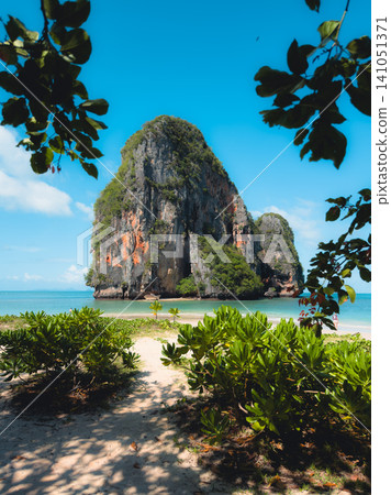 Idyllic tropical island with towering limestone karst cliffs in clear turquoise sea water. 141051371