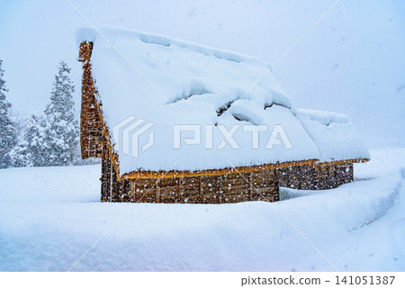 In winter in Shirakawa-go, a single gassho-zukuri house, its roof completely white, stands amidst a vast, snow-covered landscape. In winter in Shirakawa-go, a single gassho-zukuri house, its roof completely white, stands amidst a vast, snow-covered landscape. 141051387