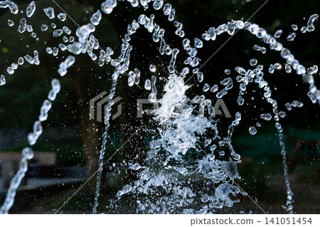 The sparkling spray of a fountain on a scorching hot day evokes a refreshing summer image. The sparkling spray of a fountain on a scorching hot day evokes a refreshing summer image. 141051454